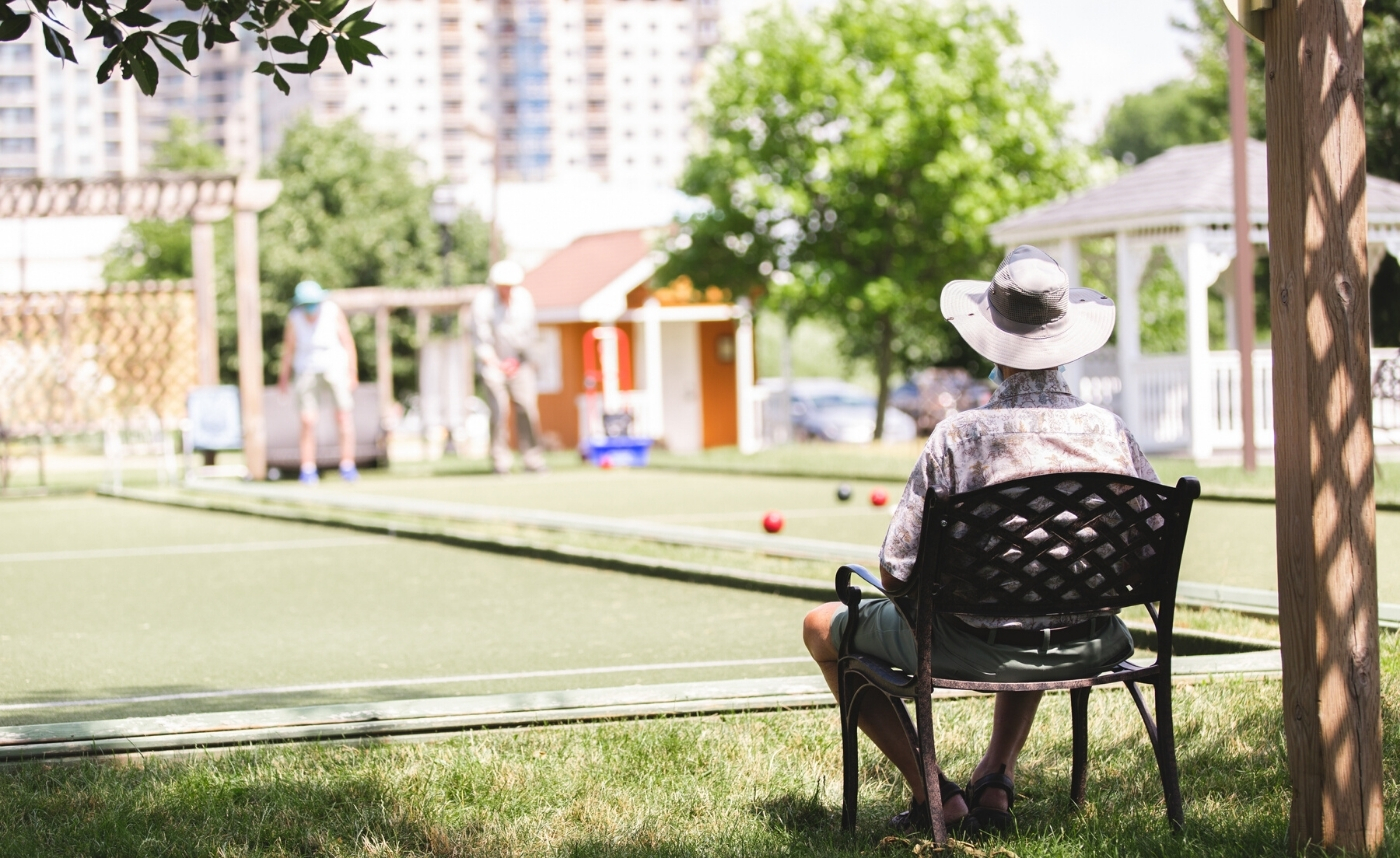 man sitting watching friends play bocce ball