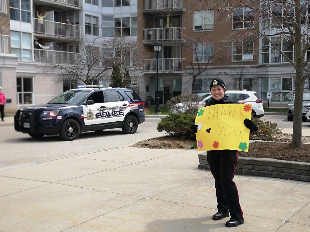 Police officer holding a thank you sign for our front line workers outside of our community