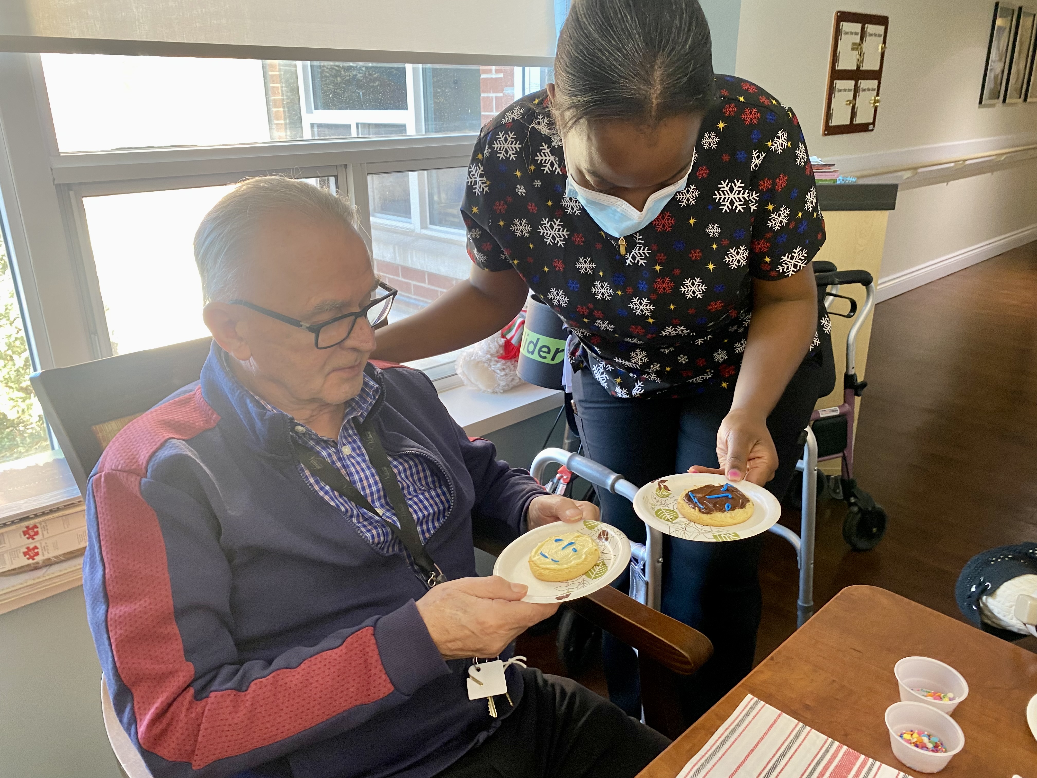 Image of resident decorating cookies with staff at Luther Village on the Park.