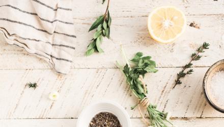 bath salts, lemon, fresh herbs all laying on a beautiful white wooden table