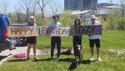 Family members holding birthday sign for a family member who is a resident