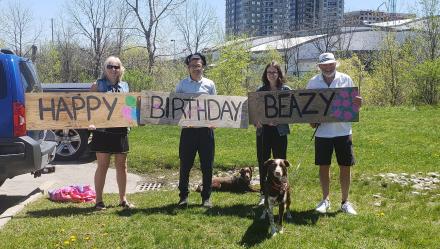 Family members holding birthday sign for a family member who is a resident