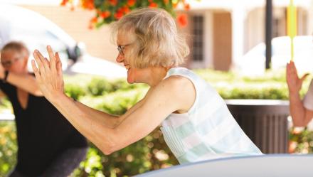 photo of resident Muriel smiling while doing yoga with friends 