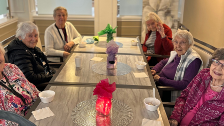 Group of women sitting at a table smiling into camera at Luther Village on the Park.