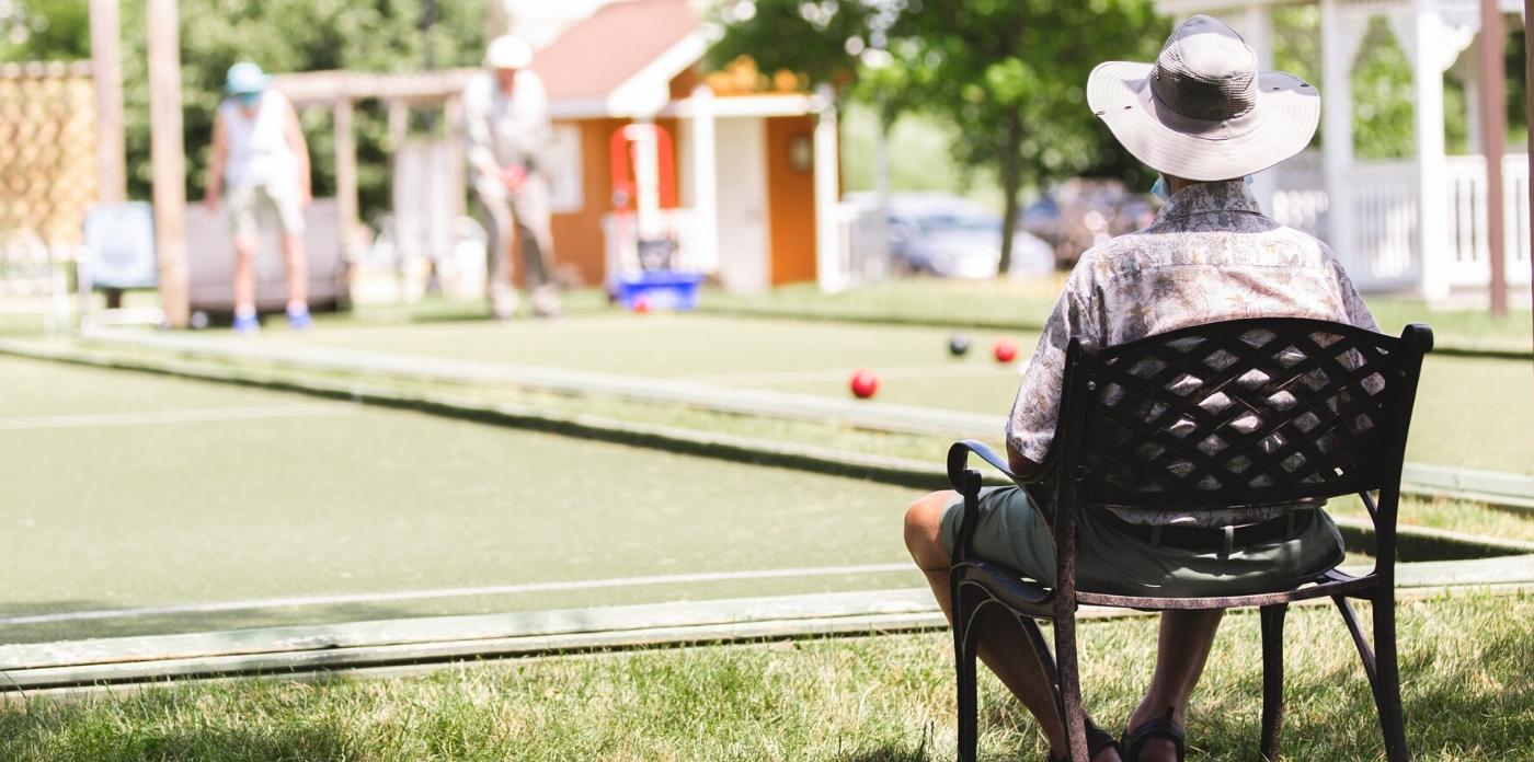 man sitting watching friends play bocce ball 