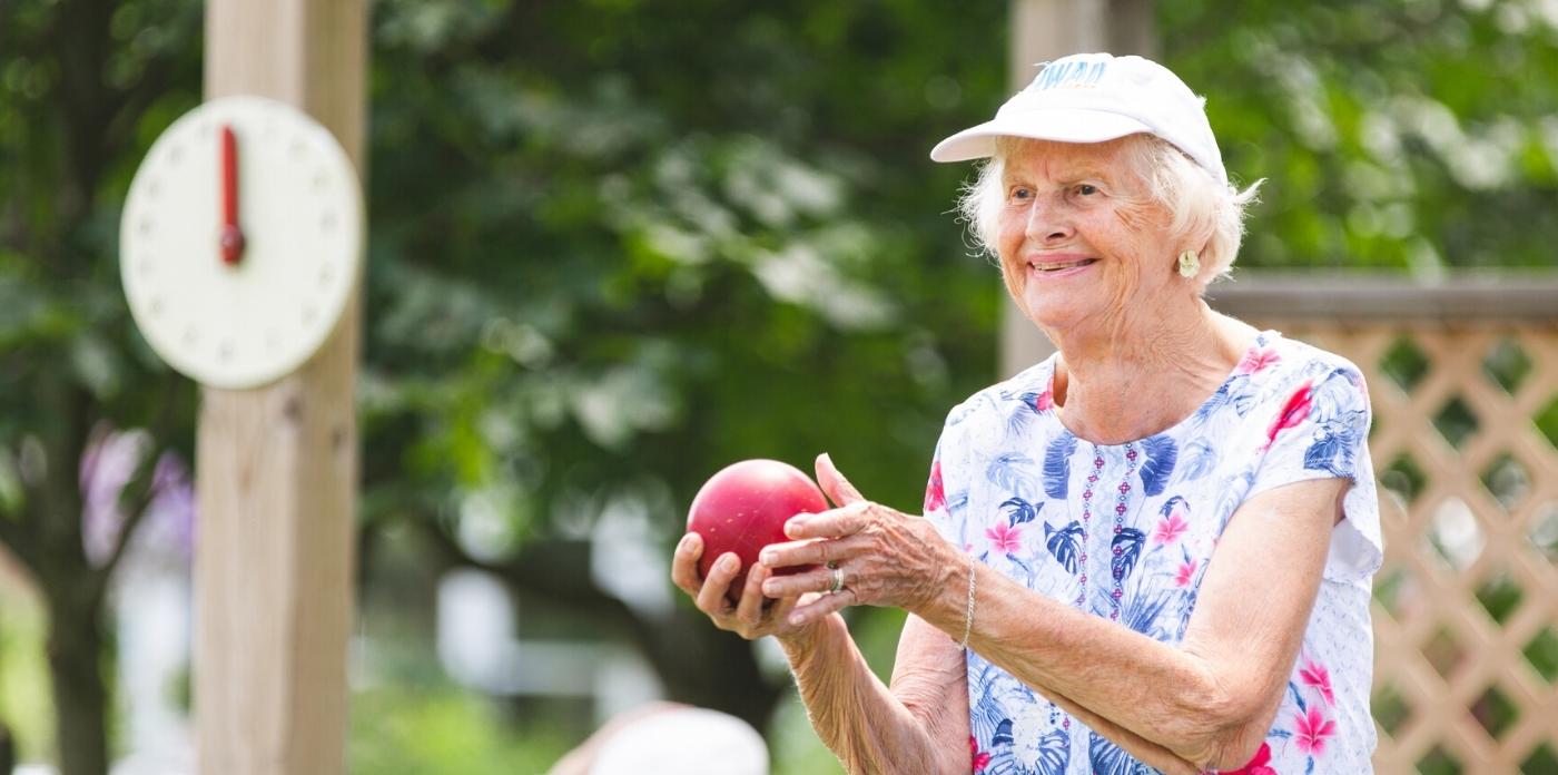 women playing bocce ball about to throw red ball 