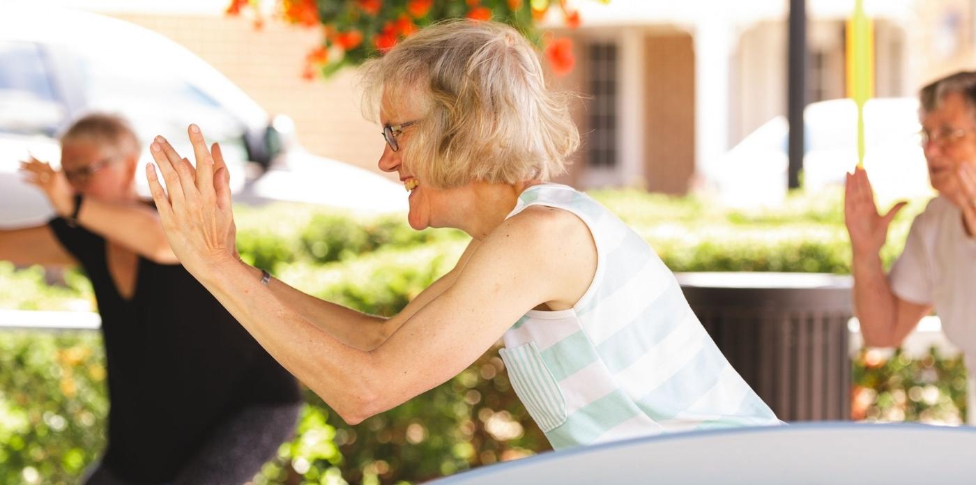 photo of resident Muriel smiling while doing yoga with friends 